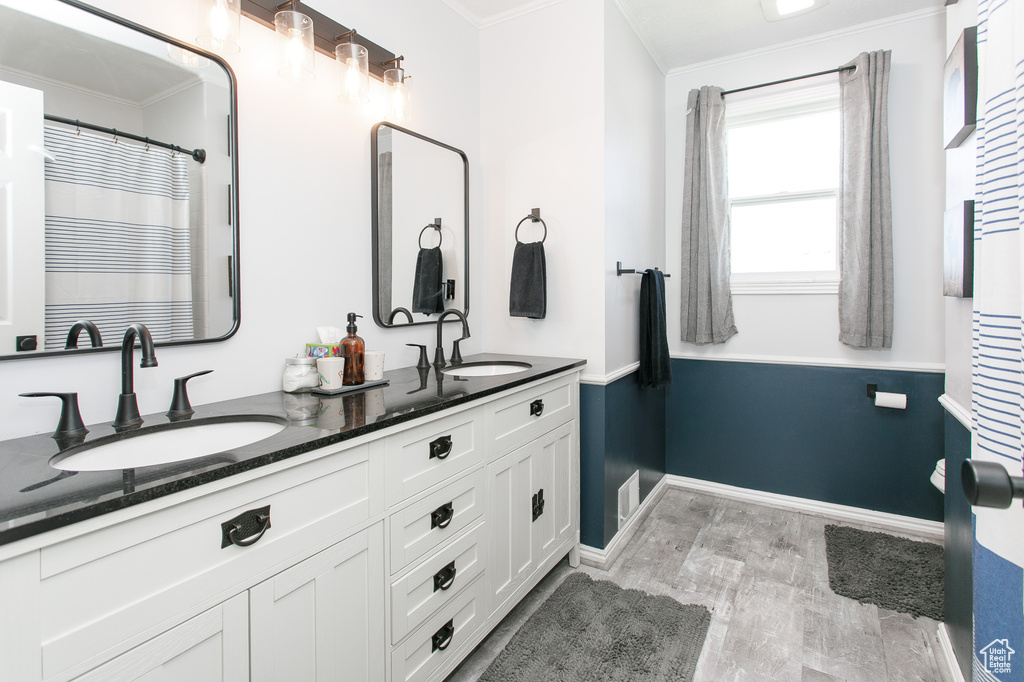 Full bath with ornamental molding, double vanity, and baseboards