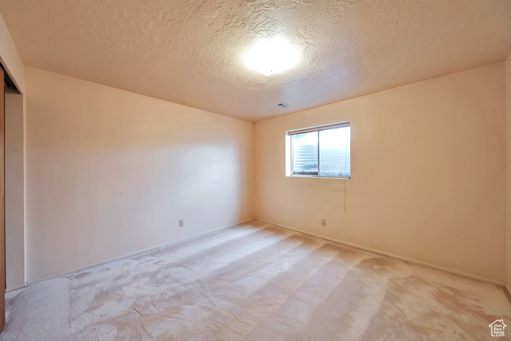 Spare room with a textured ceiling, light carpet, and baseboards