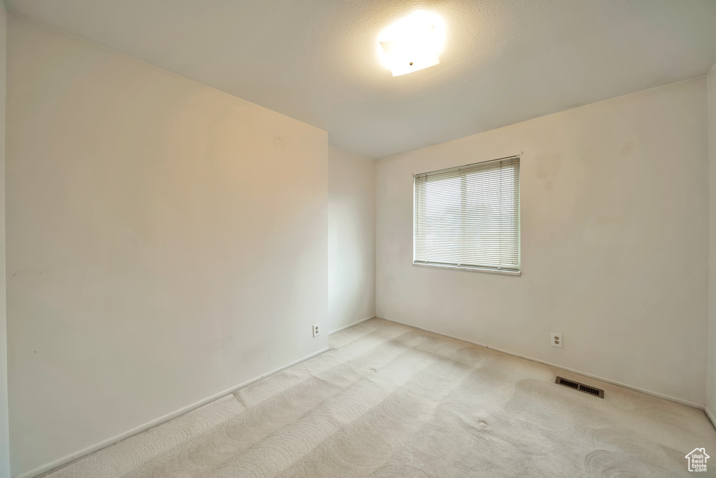 Empty room featuring light colored carpet and baseboards