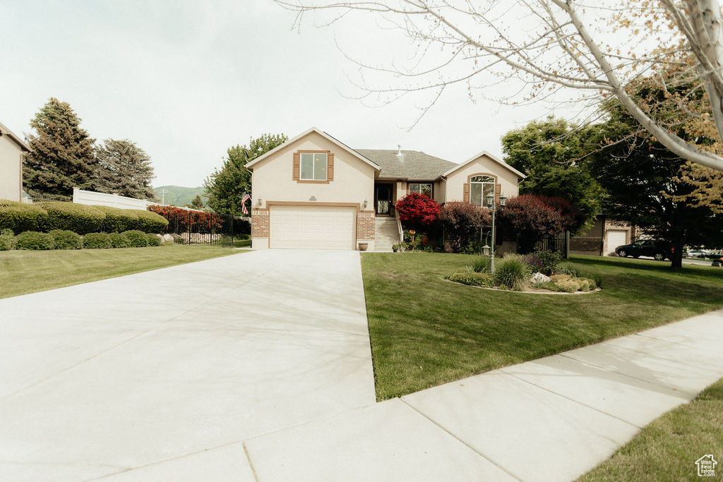 View of front facade with driveway, a garage, a front yard, and brick siding