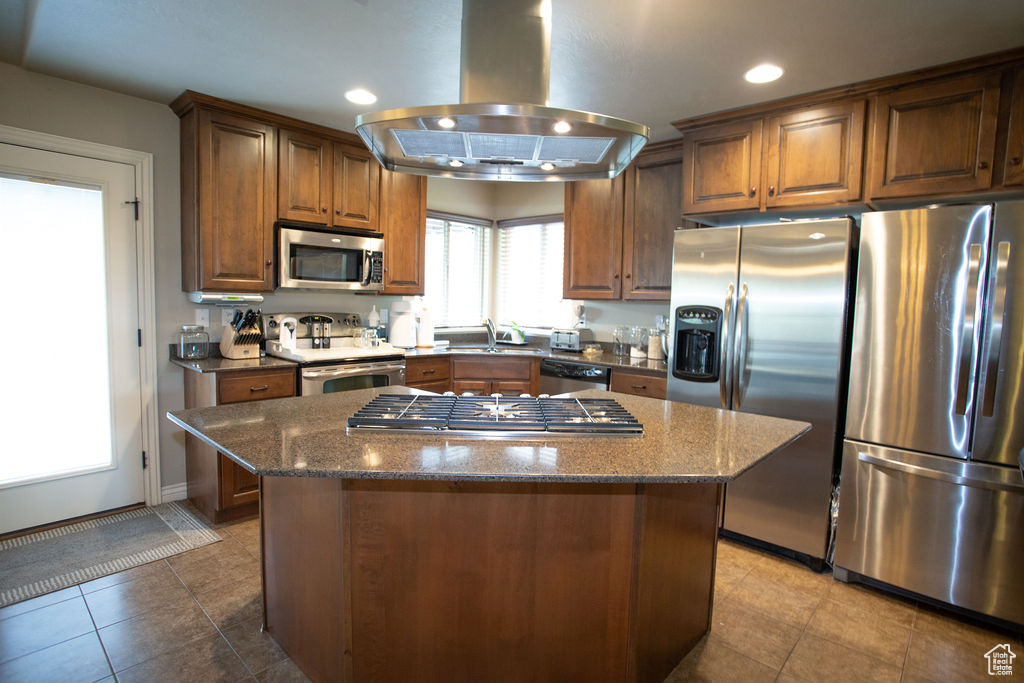 Kitchen with stainless steel appliances, island exhaust hood, a sink, recessed lighting, and dark stone counters