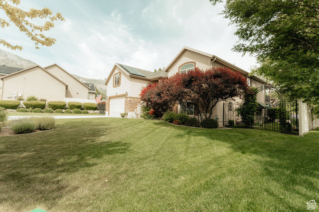 View of side of property with an attached garage, roof mounted solar panels, stucco siding, and concrete driveway