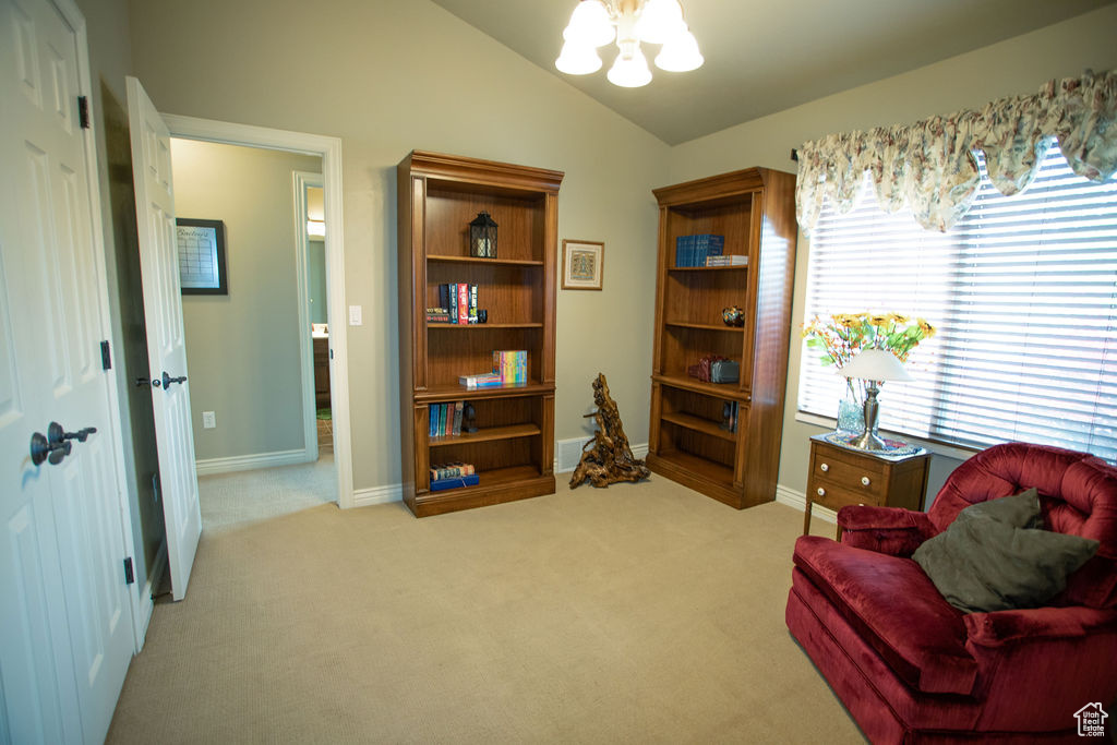Living area featuring a chandelier, vaulted ceiling, light colored carpet, and baseboards