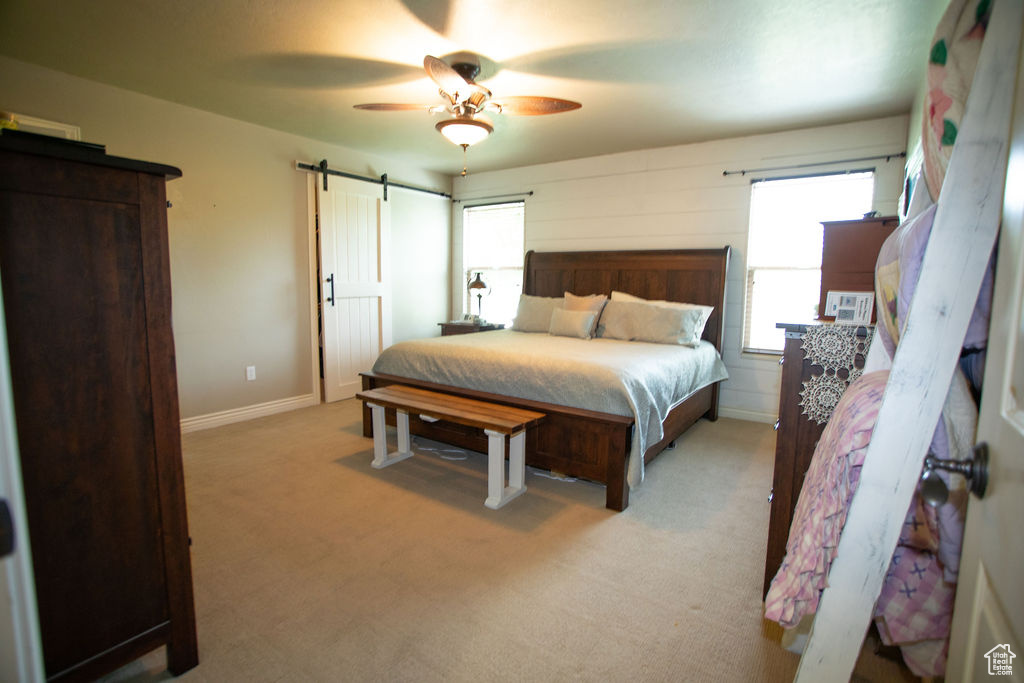 Bedroom with a barn door, carpet, baseboards, and ceiling fan