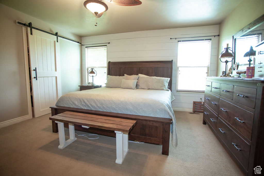 Bedroom with a barn door, light carpet, and baseboards