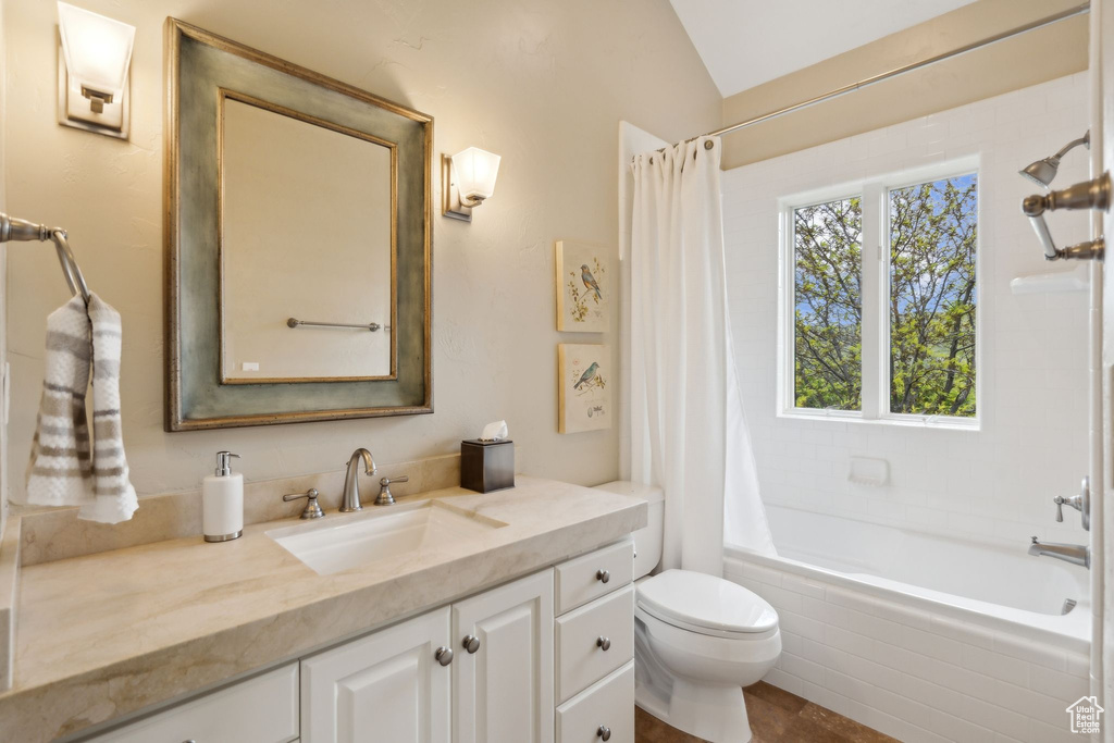 Full bathroom with vanity, tiled shower / bath combo, toilet, and vaulted ceiling
