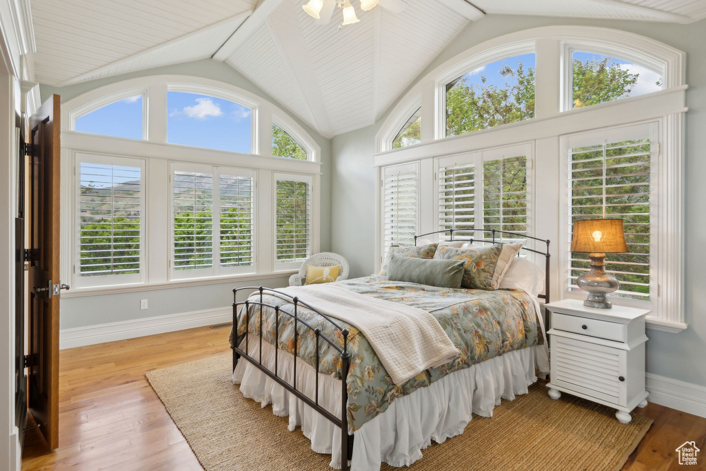 Bedroom with lofted ceiling, baseboards, and light wood-style floors