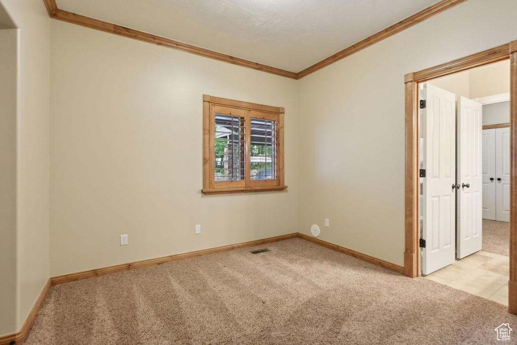 Unfurnished room with light carpet, ornamental molding, and baseboards
