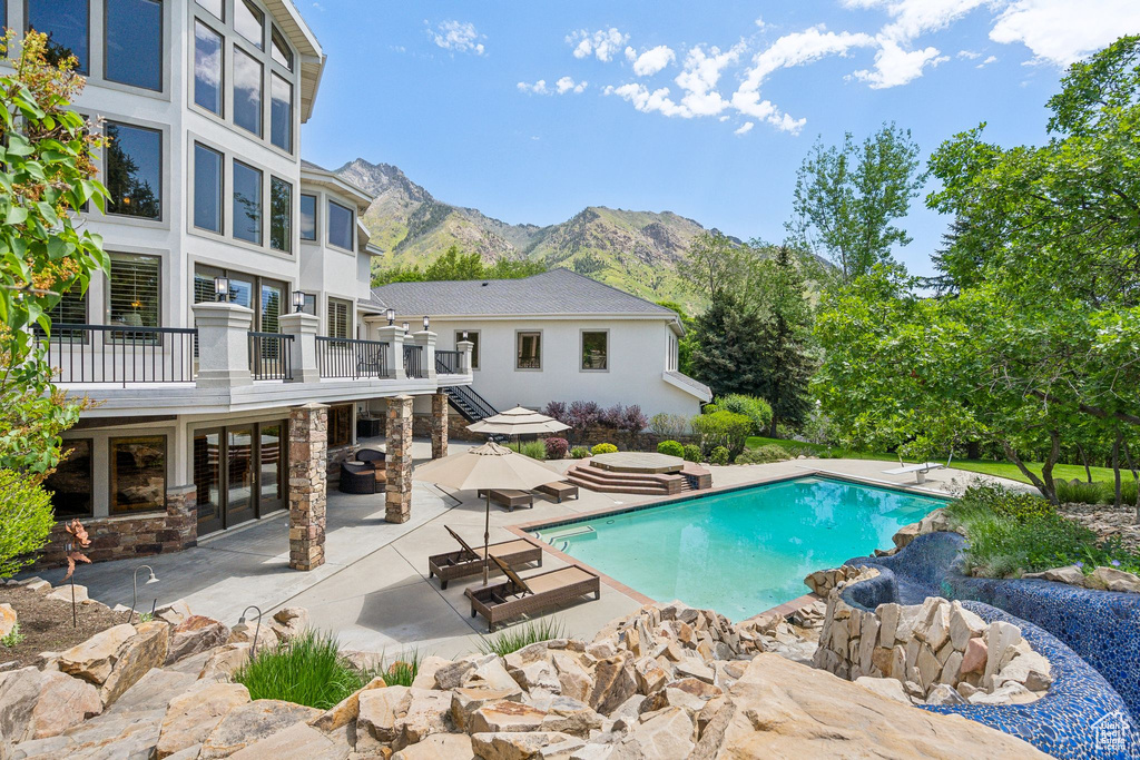 Swimming pool featuring a patio area, a diving board, french doors, and a deck with mountain view