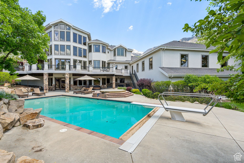 Outdoor pool with a patio, stairs, and a diving board