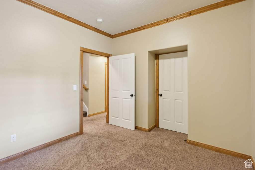 Unfurnished room featuring crown molding, carpet, baseboards, and a smoke detector