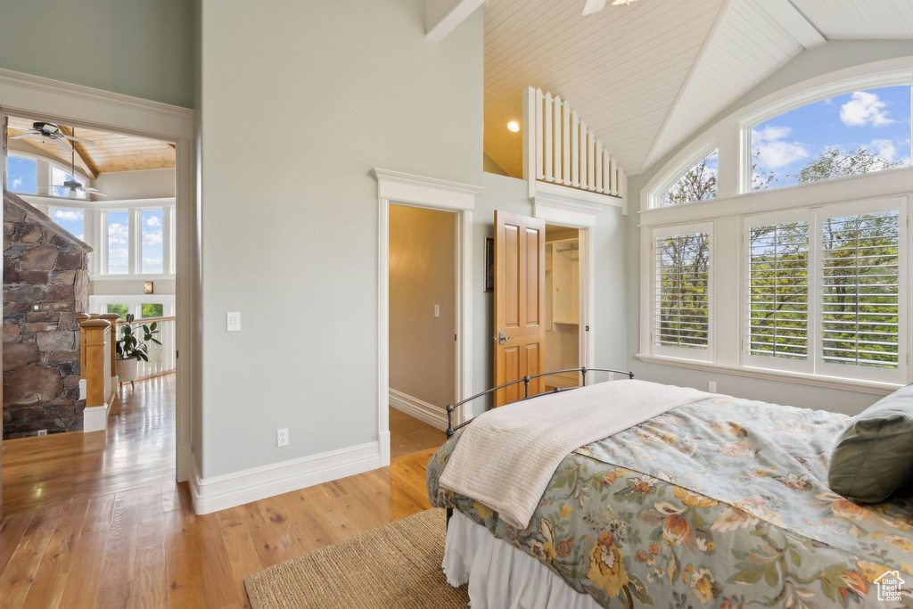 Bedroom with high vaulted ceiling, light wood-style flooring, and baseboards