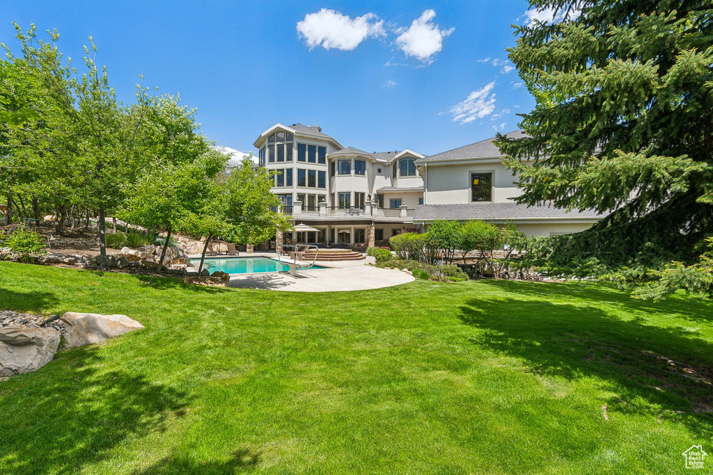 Back of house with an outdoor pool, a patio area, and a yard