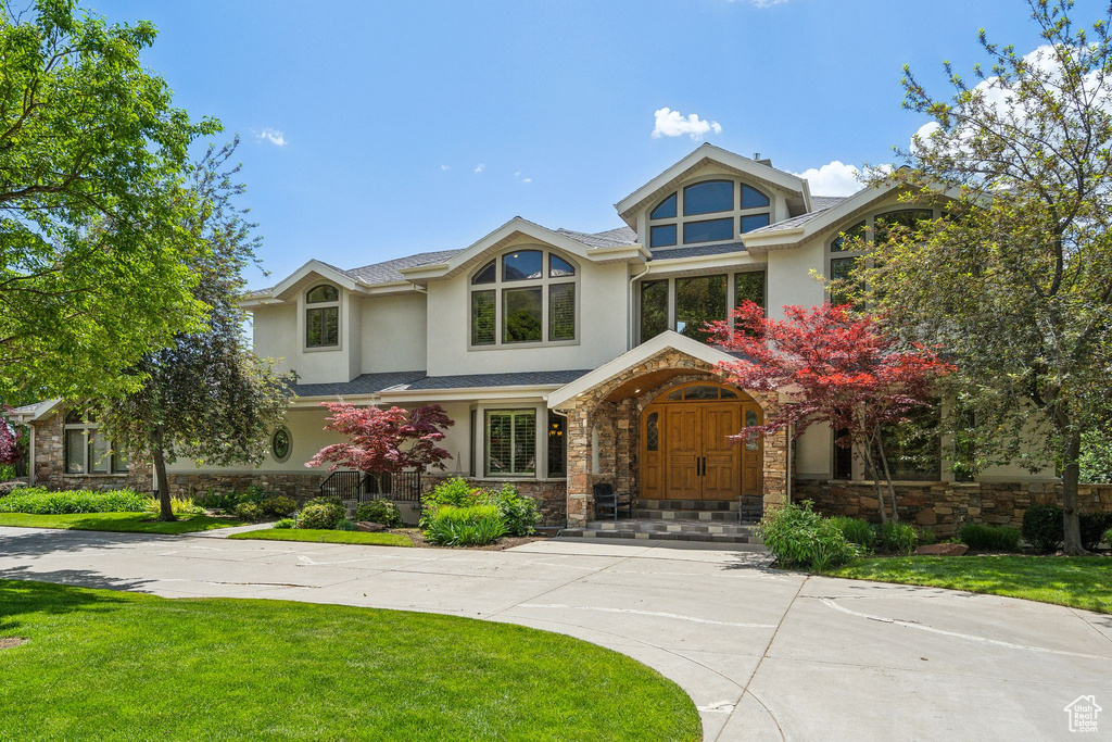 Tudor-style house featuring stucco siding, stone siding, and a front yard