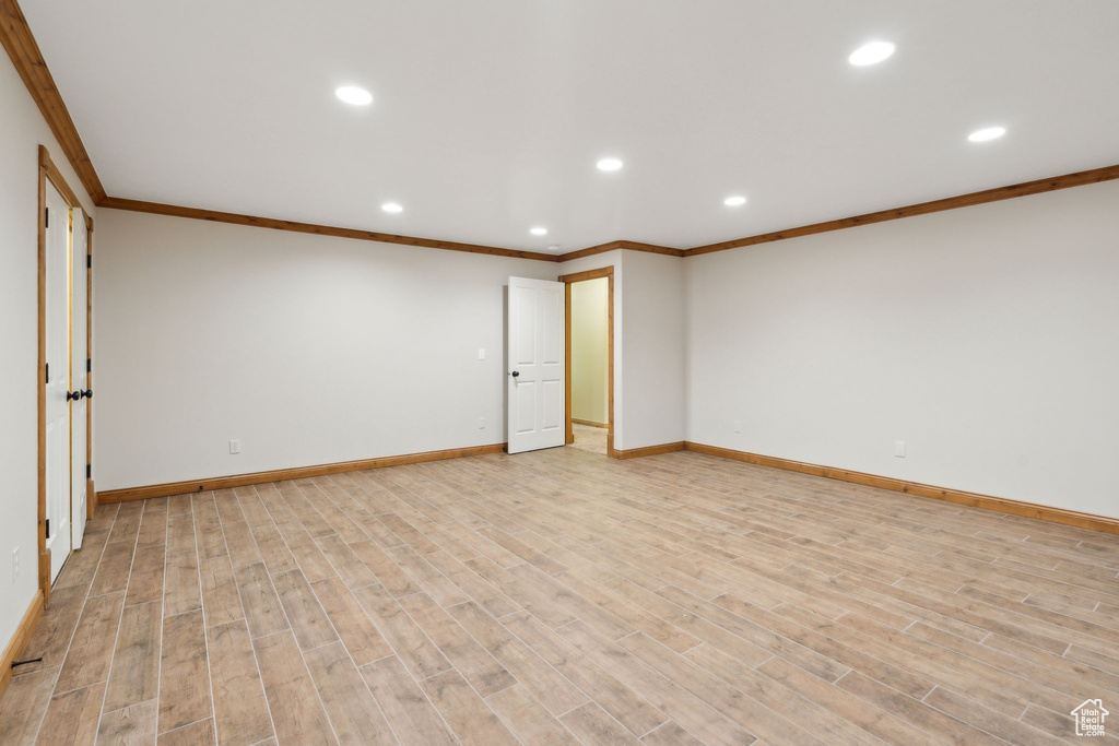 Empty room with ornamental molding, recessed lighting, baseboards, and light wood-type flooring