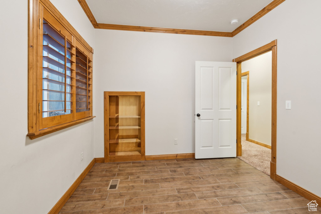 Spare room with crown molding, wood finished floors, baseboards, and a smoke detector