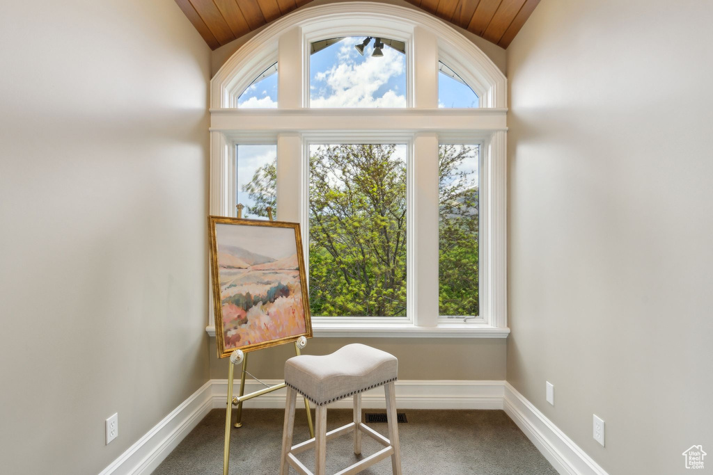 Living area featuring vaulted ceiling, plenty of natural light, wood ceiling, and carpet