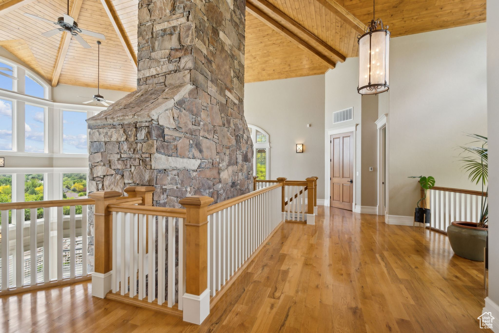 Corridor with high vaulted ceiling, wood ceiling with exposed beams, wood finished floors, an upstairs landing, and baseboards