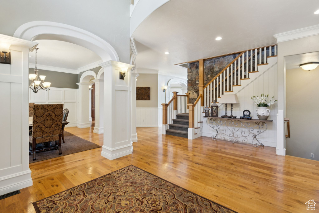 Foyer entrance with a decorative wall, arched walkways, decorative columns, wood finished floors, and stairway