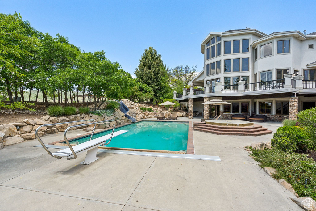 Outdoor pool featuring a diving board and a patio area