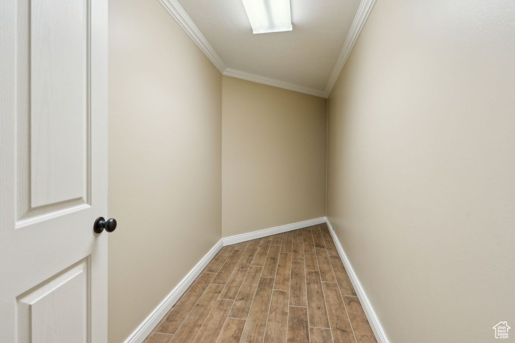 Empty room featuring crown molding, light wood-type flooring, and baseboards