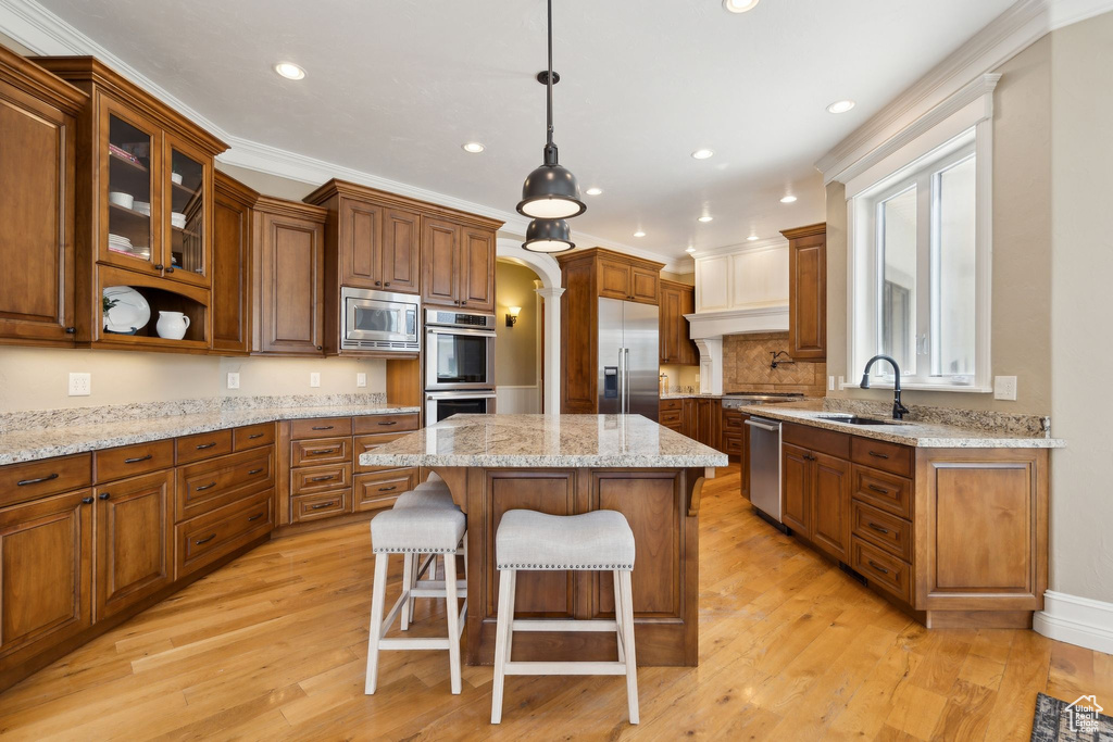 Kitchen featuring built in appliances, a sink, recessed lighting, a kitchen breakfast bar, and a center island