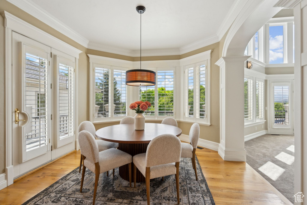 Dining room featuring plenty of natural light, light wood-style floors, crown molding, and baseboards