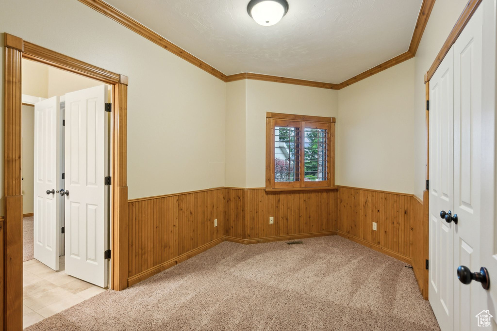 Spare room featuring wainscoting, ornamental molding, and wooden walls