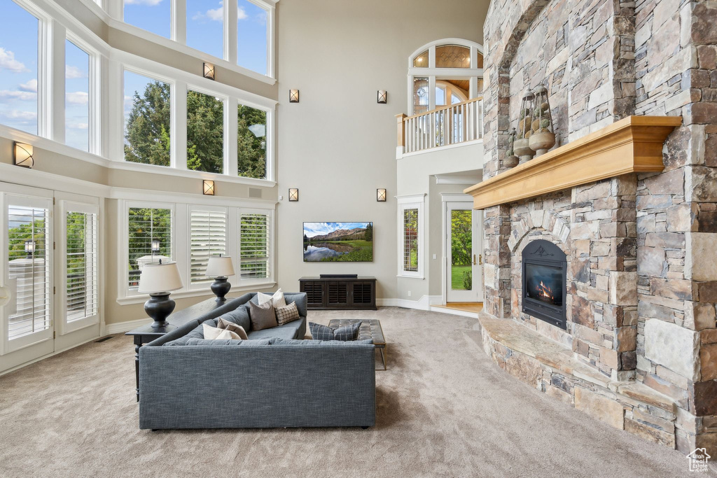 Carpeted living area with a high ceiling, a fireplace, and baseboards