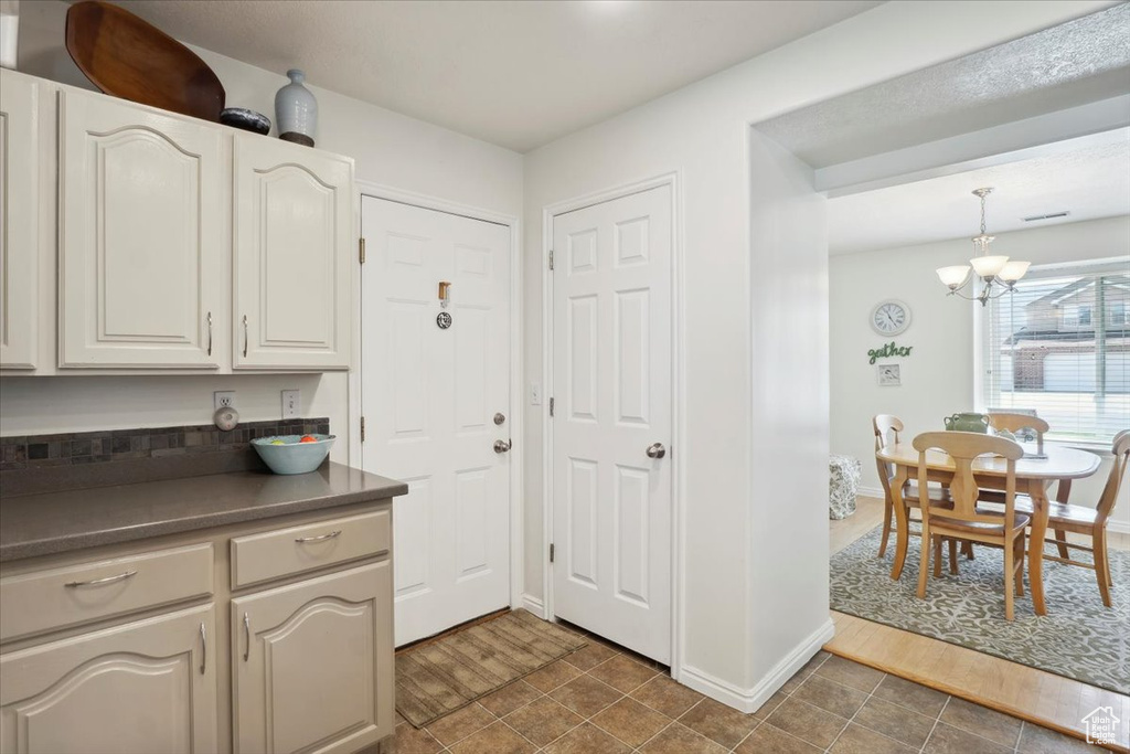 Kitchen with dark countertops, a chandelier, baseboards, and decorative light fixtures