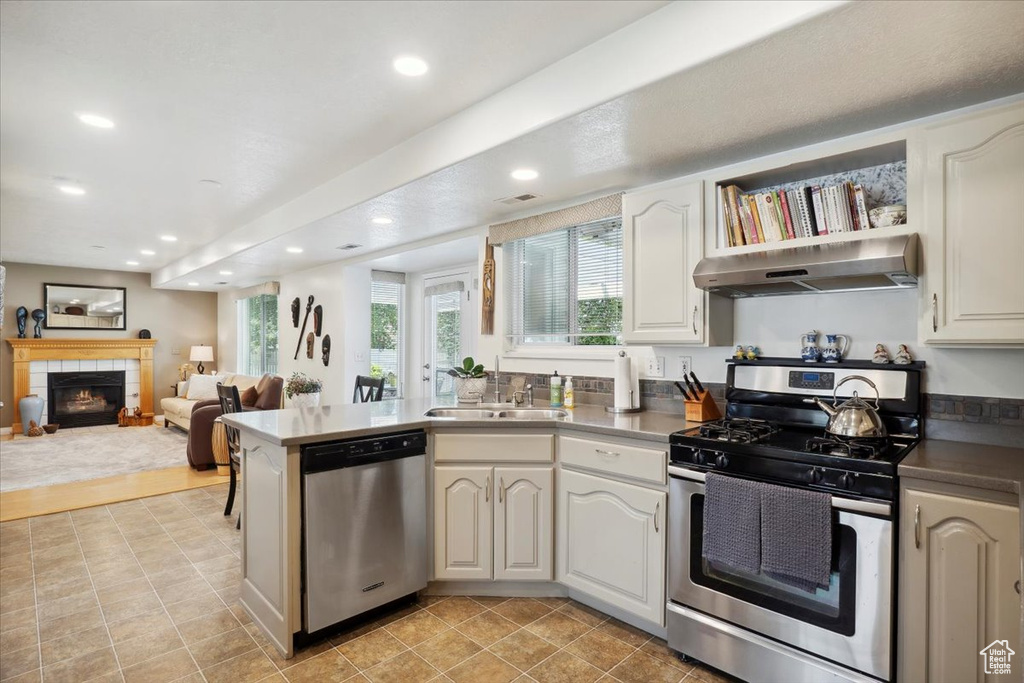 Kitchen featuring appliances with stainless steel finishes, under cabinet range hood, a sink, a peninsula, and recessed lighting