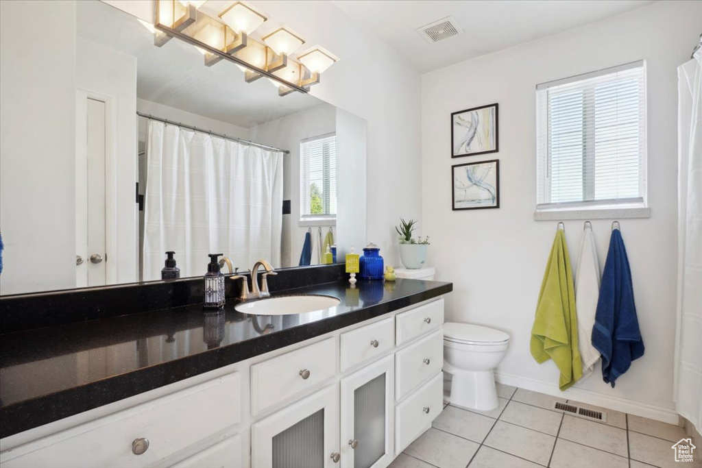 Full bath with toilet, vanity, tile patterned floors, and baseboards