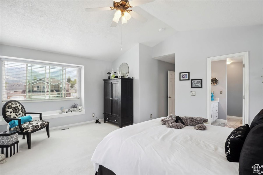 Bedroom featuring vaulted ceiling, baseboards, light colored carpet, and a ceiling fan