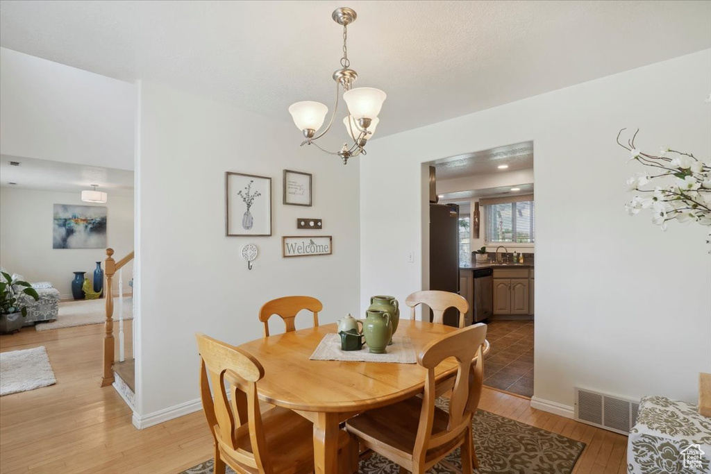 Dining area featuring light wood-style flooring, a chandelier, and baseboards
