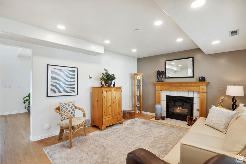 Living room with recessed lighting, light wood-type flooring, a tiled fireplace, and baseboards