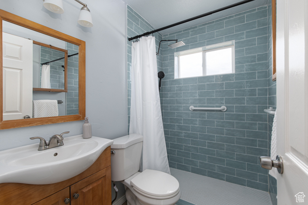 Full bath with vanity, toilet, and a tile shower