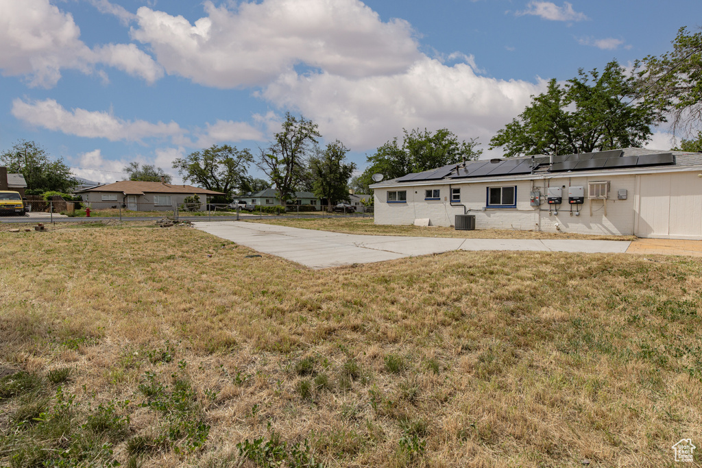 View of green lawn featuring concrete driveway and central AC unit