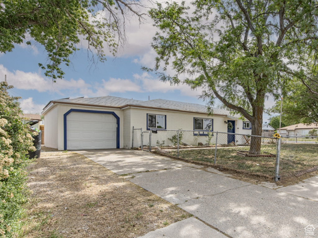 Single story home featuring a fenced front yard, driveway, and an attached garage