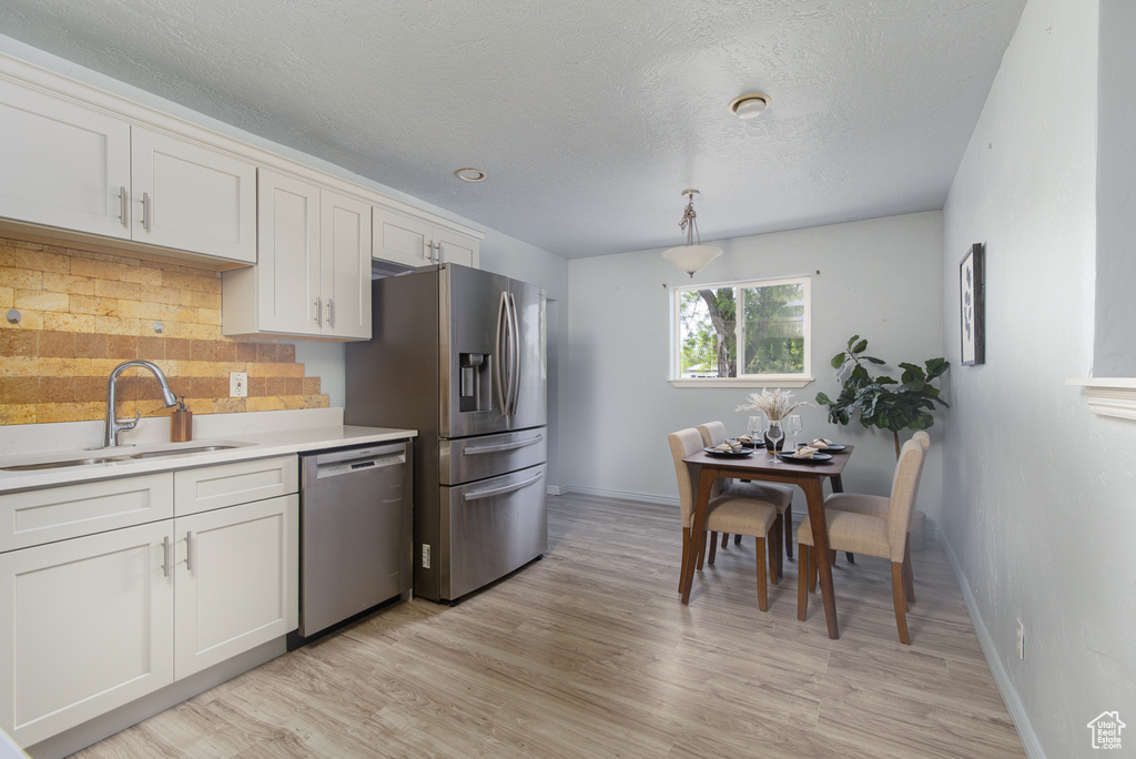 Kitchen with stainless steel appliances, a sink, decorative backsplash, baseboards, and light countertops