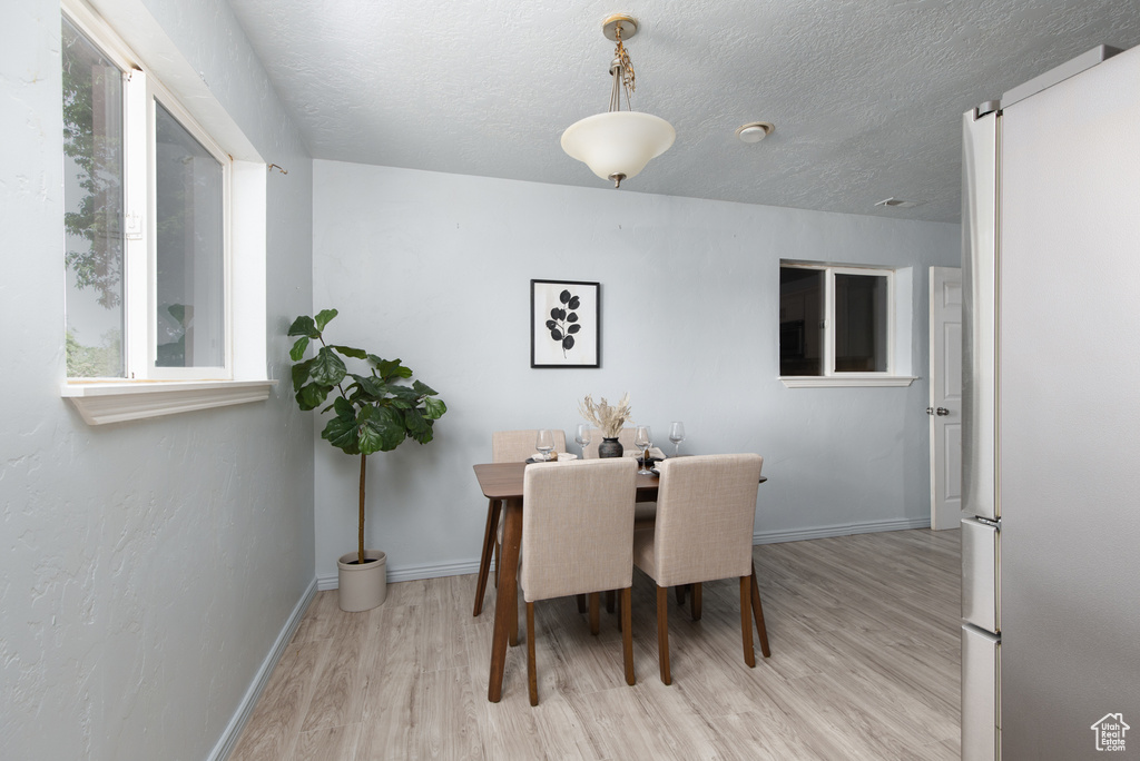 Dining area featuring light wood-type flooring, baseboards, and a textured ceiling
