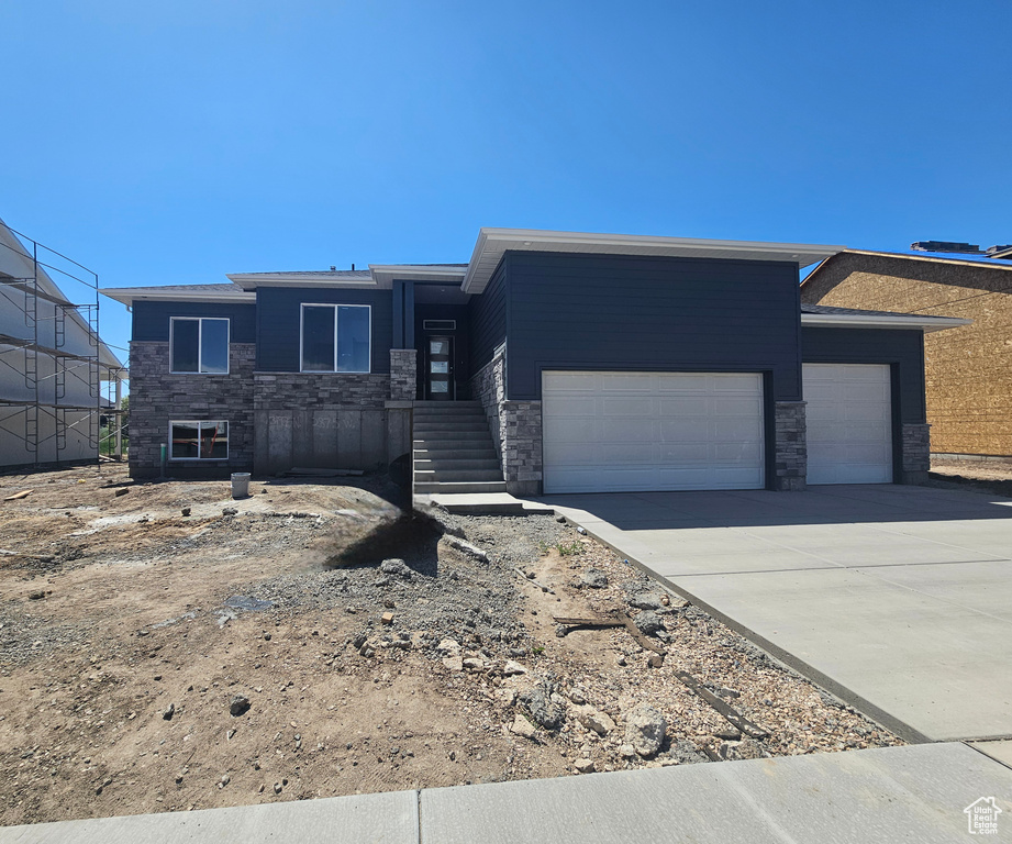 Prairie-style house featuring stone siding, a garage, and driveway