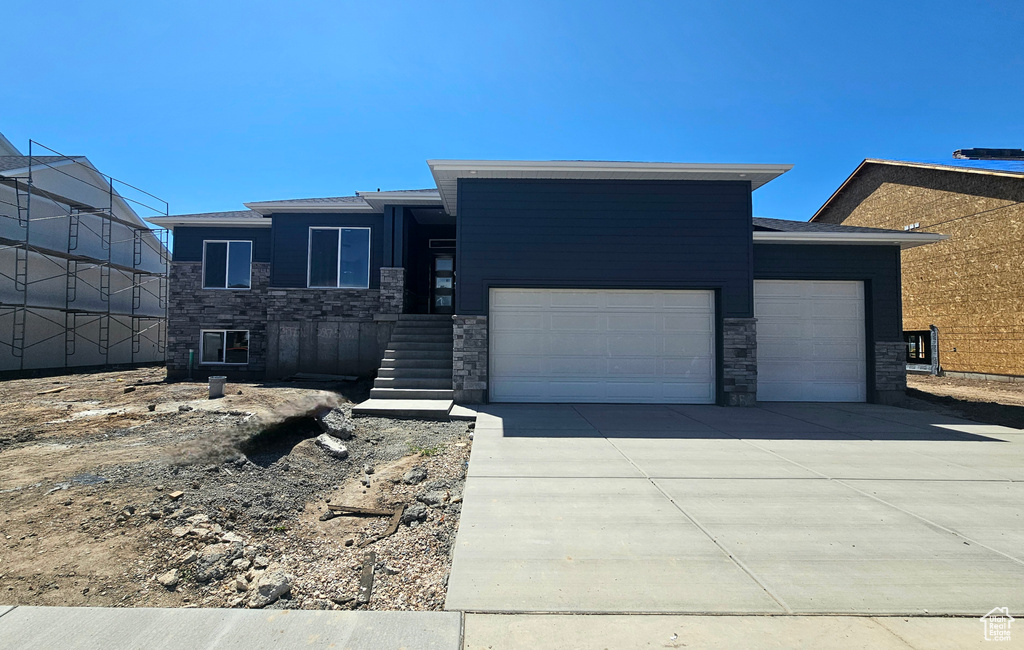 Prairie-style home with stone siding, an attached garage, and concrete driveway
