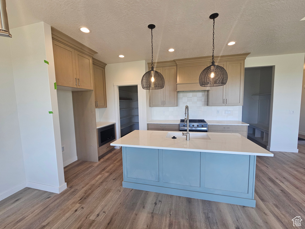 Kitchen with baseboards, light countertops, tasteful backsplash, wood finished floors, and a textured ceiling