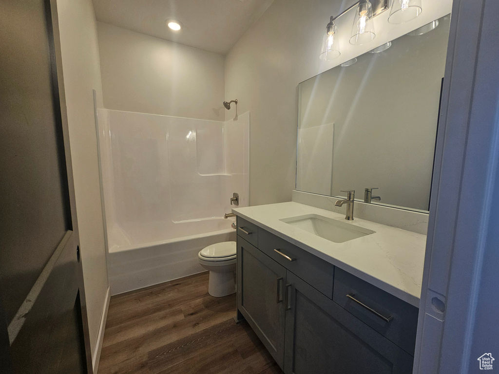 Bathroom featuring wood finished floors, vanity, toilet,  shower combination, and recessed lighting
