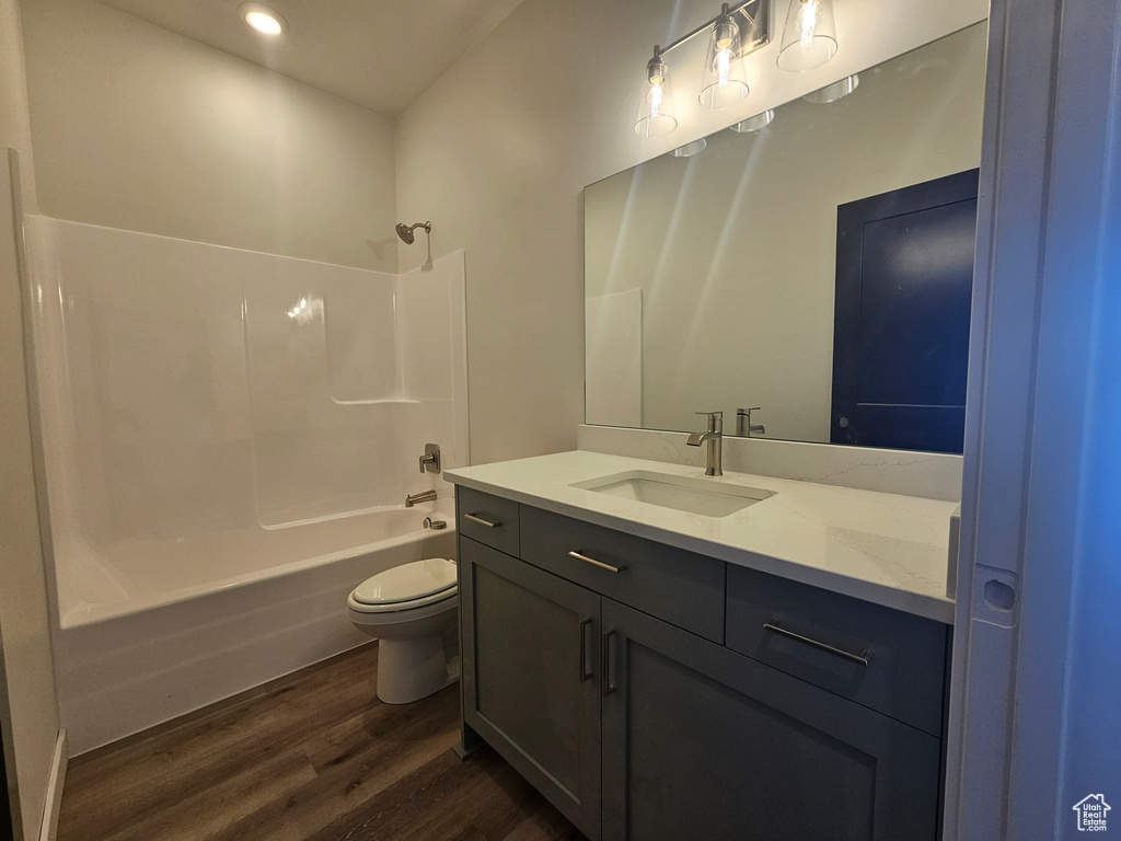 Bathroom featuring wood finished floors, vanity, toilet, shower / washtub combination, and recessed lighting