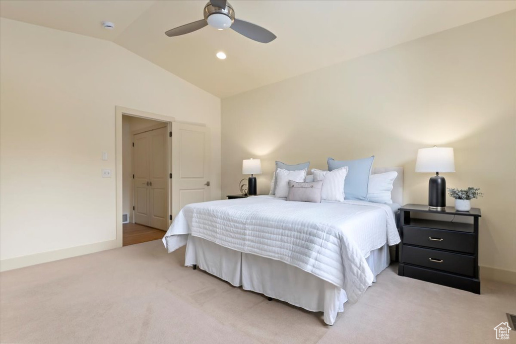 Bedroom with vaulted ceiling, light colored carpet, baseboards, and a ceiling fan