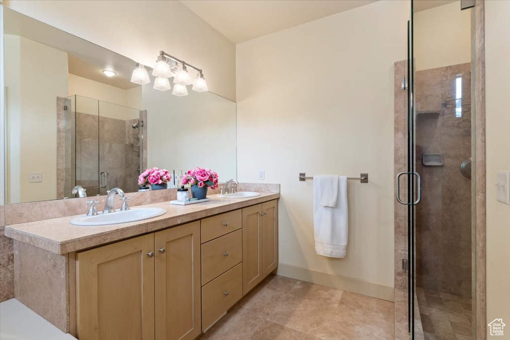 Bathroom featuring double vanity, a shower stall, and baseboards