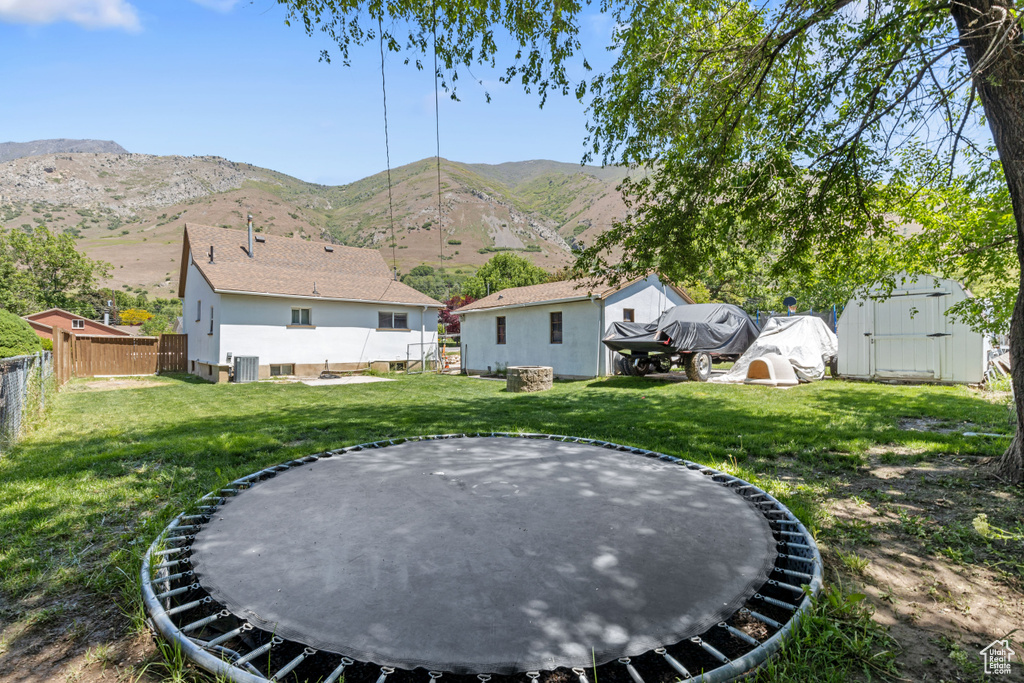View of yard with a trampoline, a mountain view, and central AC