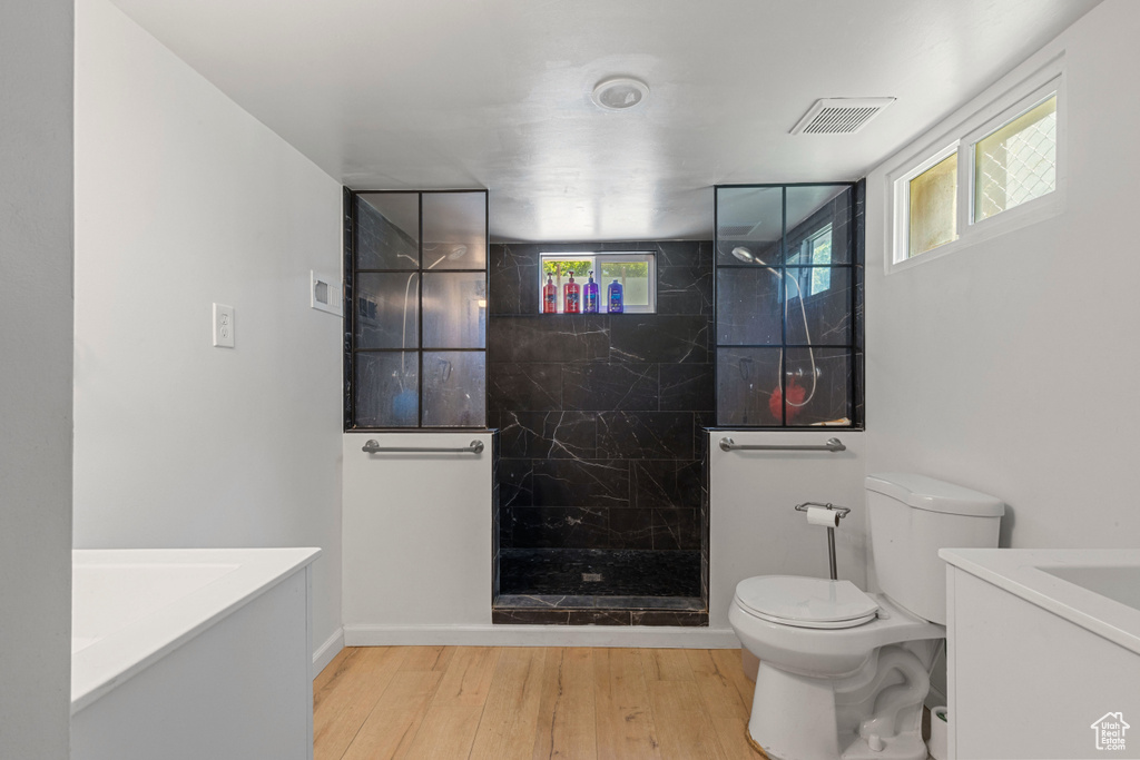 Bathroom with vanity, toilet, wood finished floors, a marble finish shower, and baseboards