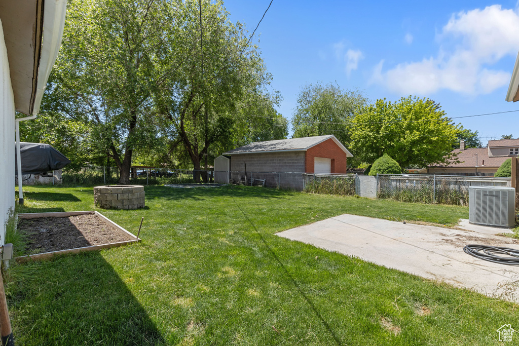 View of yard featuring central AC unit, a detached garage, and a patio area